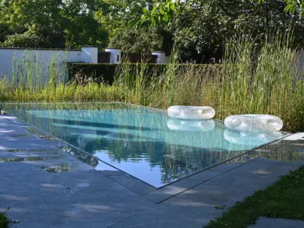 Hybridpool auf Salzwasserbasis als Überlaufpool mit Sonnenliegen im Wasser
