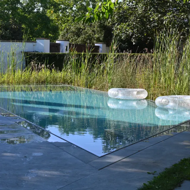 Hybridpool auf Salzwasserbasis als Überlaufpool mit Sonnenliegen im Wasser