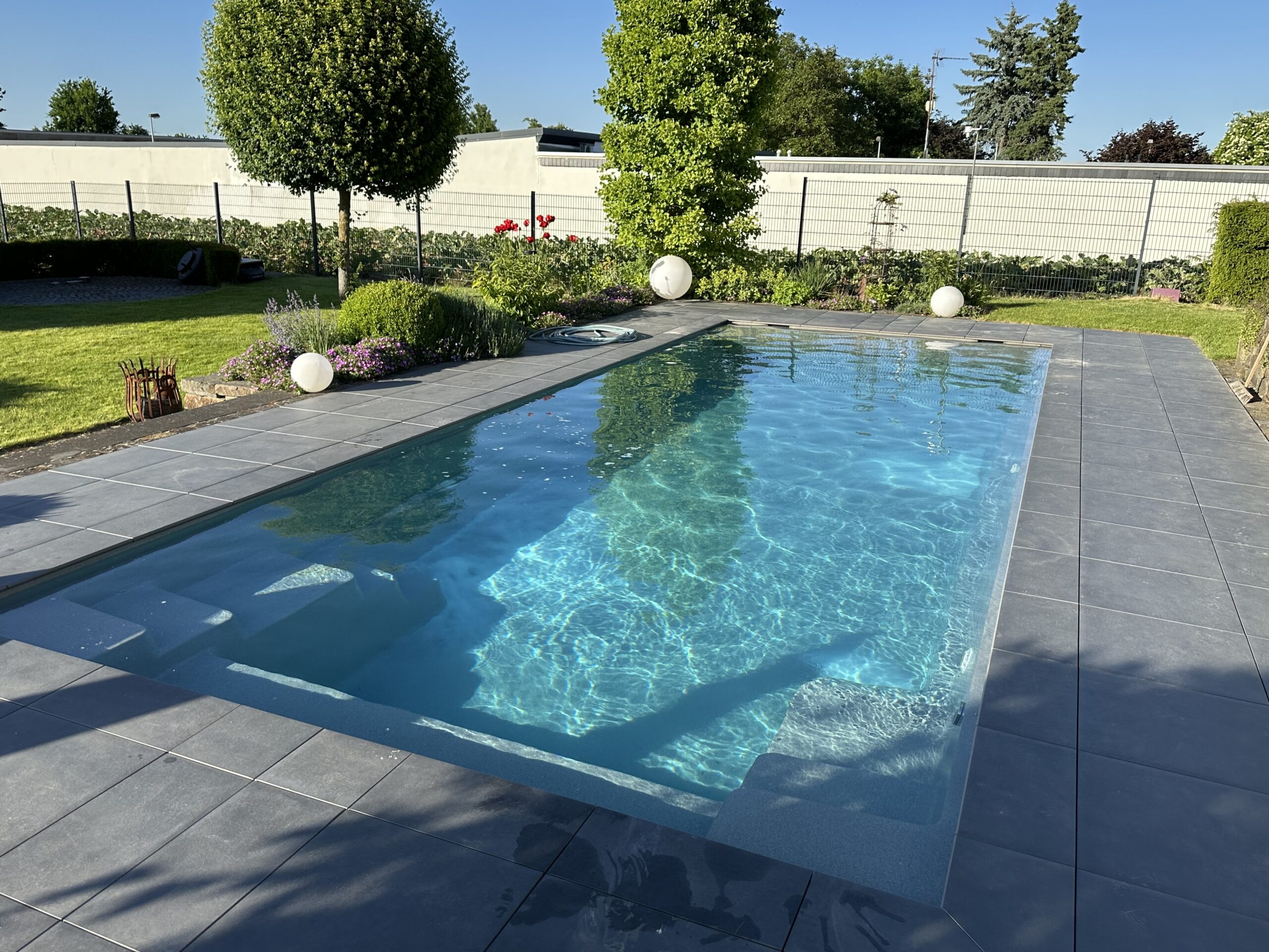 Geradliniger Pool mit bepflanztem Gartenumfeld