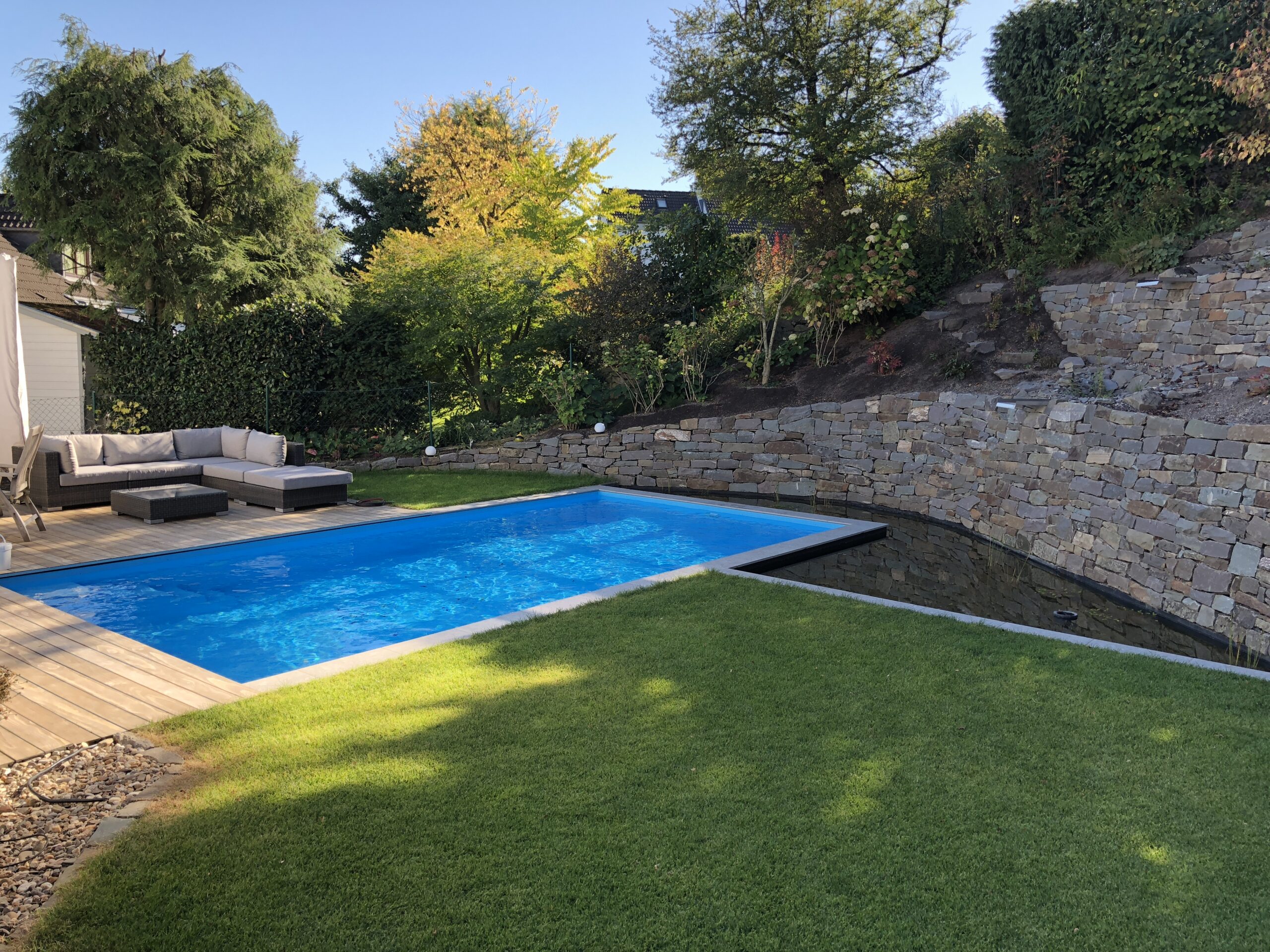 Pool mit Natursteinmauer und Holzbelag