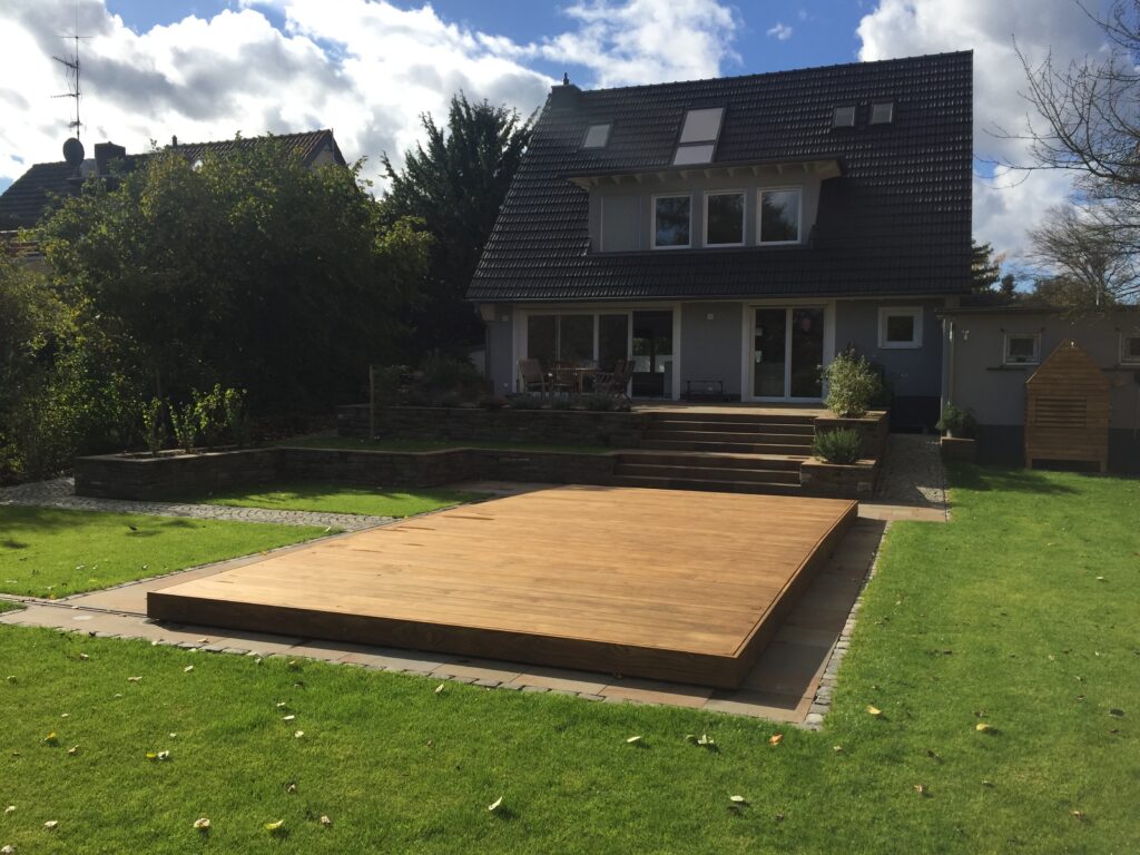 Poolbereich mit Holzdeck und angrenzenden Gartenflächen