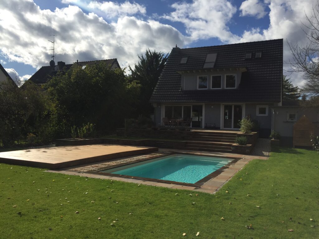 Pool mit Holzabdeckung und Gartenwegen