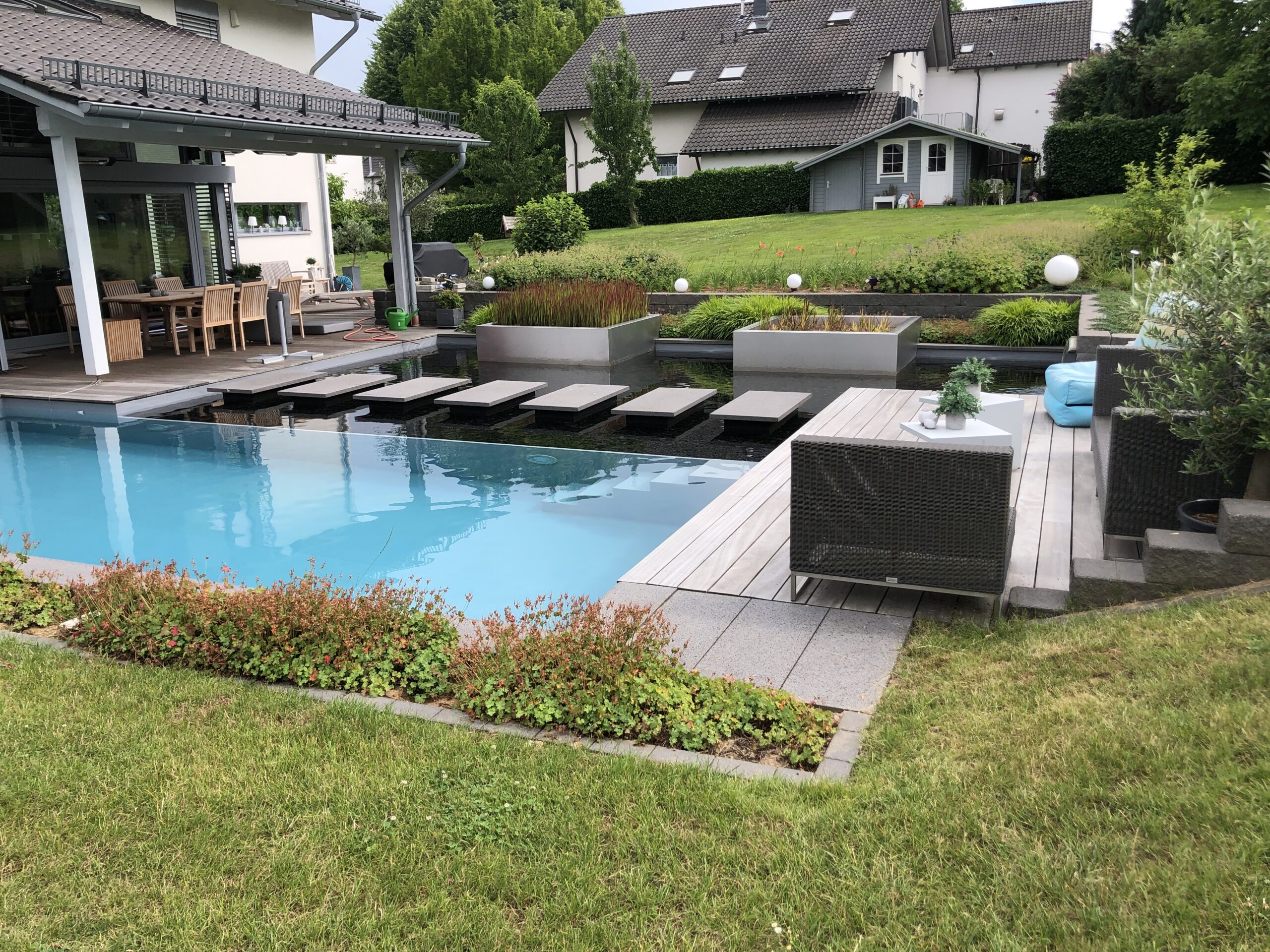 Hybridpool mit Natursteinelementen und Holzterrasse