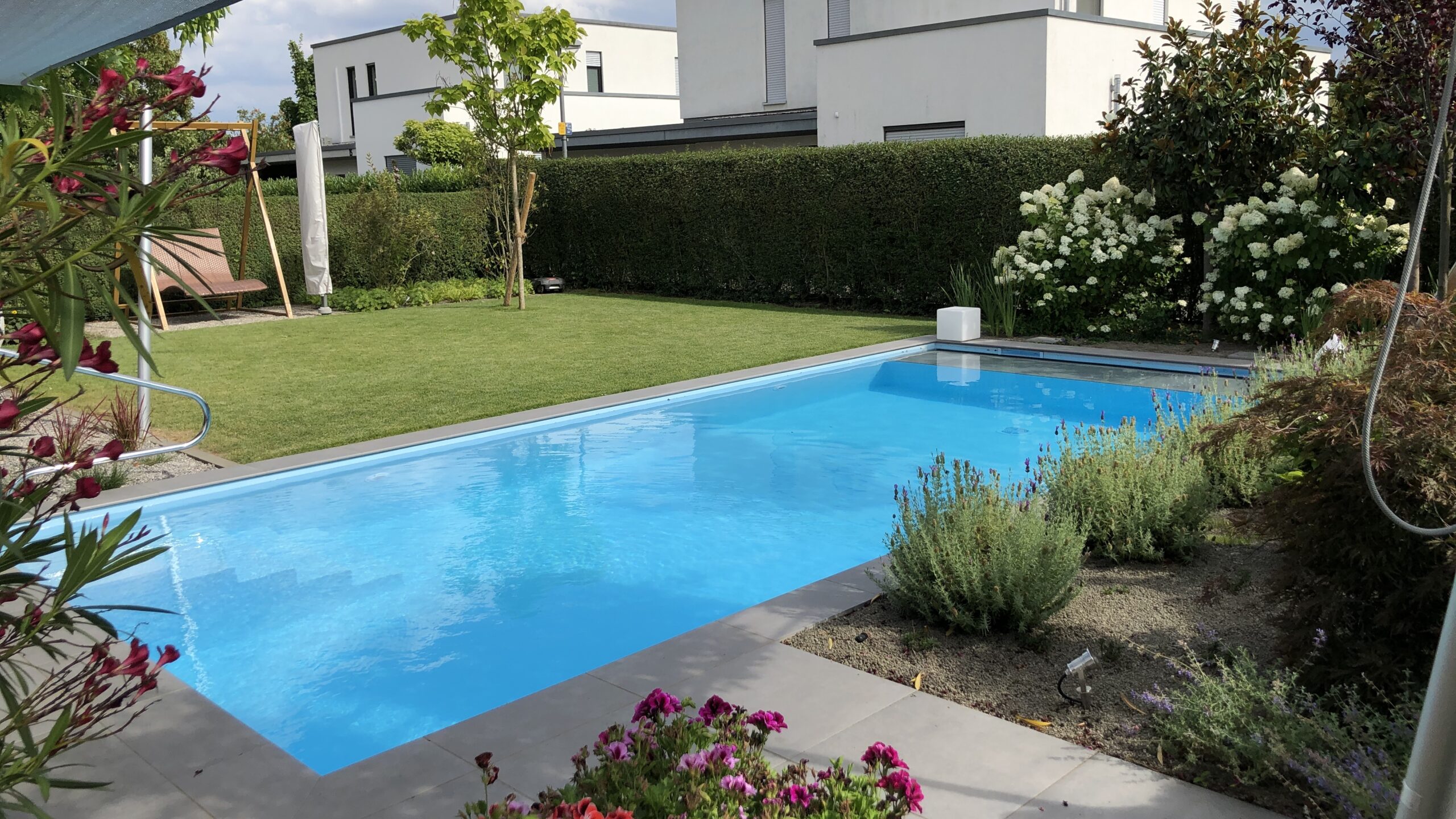 Poolanlage mit Blütengarten und Terrassenfläche
