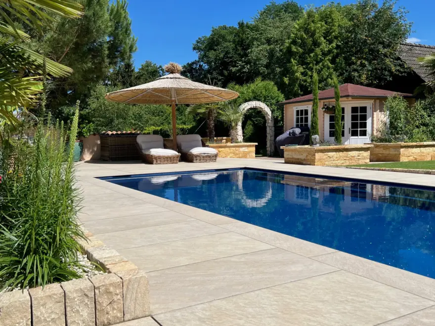Moderner Pool mit heller Terrassenfläche und Poolhaus