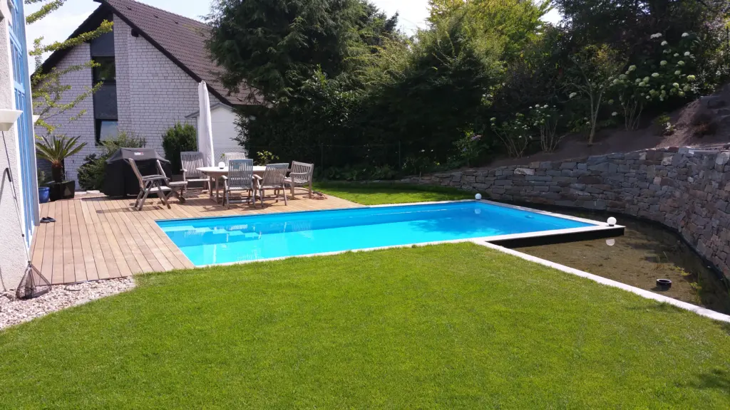 Pool mit Natursteinmauer und Holzbelag