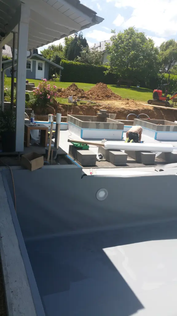 Hybridpool mit Natursteinelementen und Holzterrasse