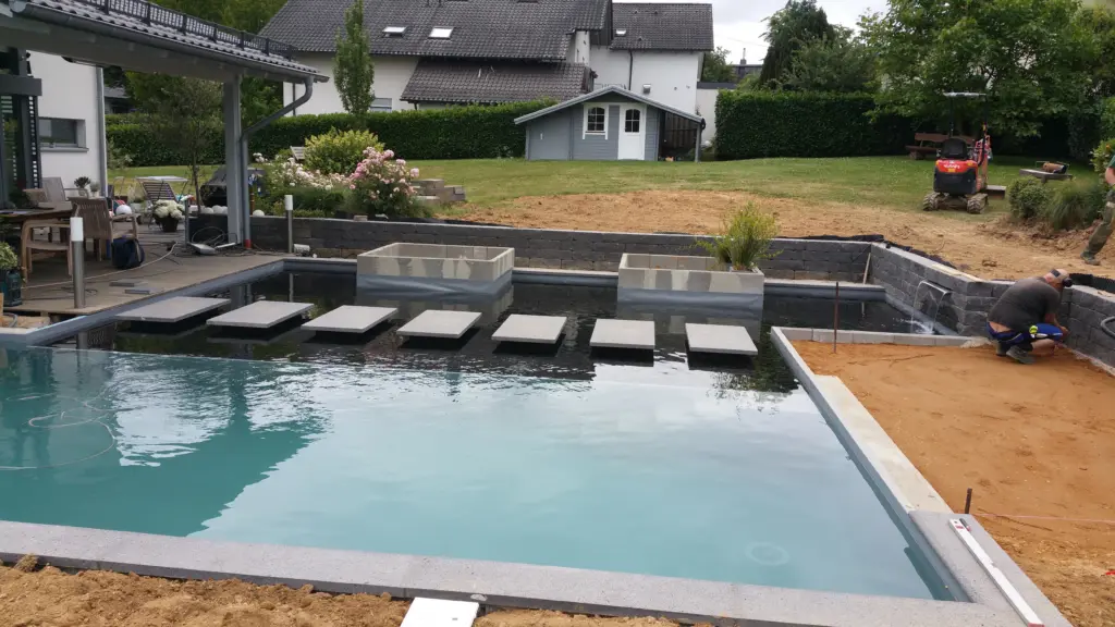 Hybridpool mit Natursteinelementen und Holzterrasse