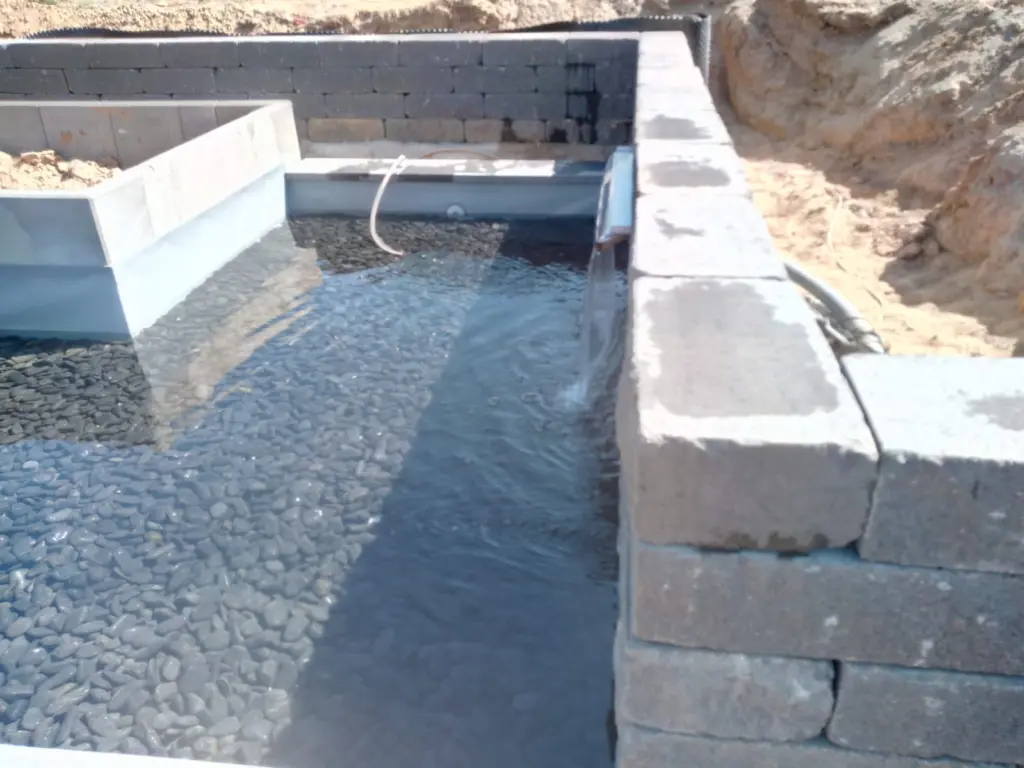 Hybridpool mit Natursteinelementen und Holzterrasse
