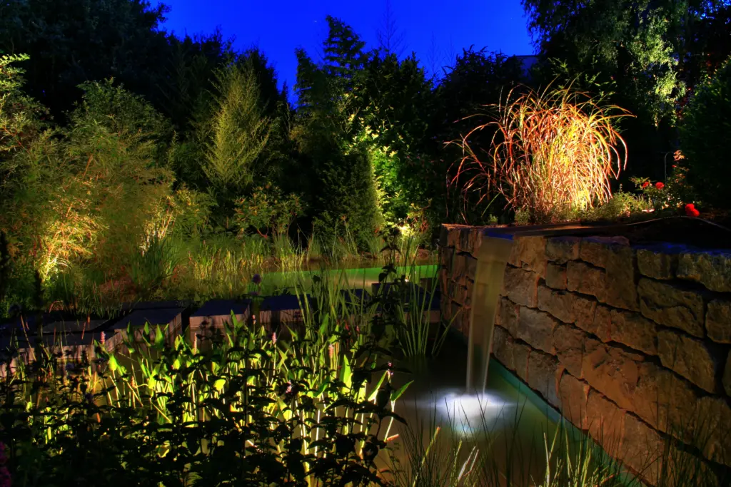 Schwimmteich mit Gartenbeleuchtung und bepflanztem Uferbereich