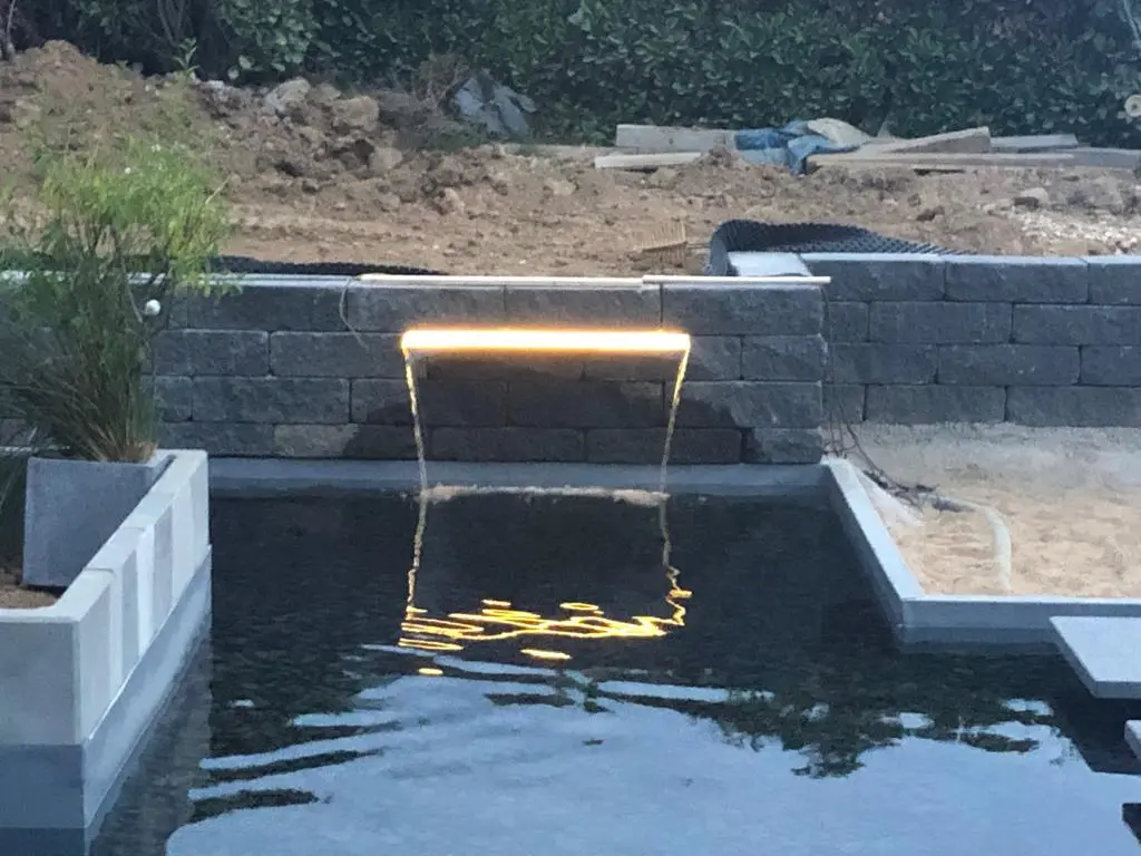 Hybridpool mit Natursteinelementen und Holzterrasse