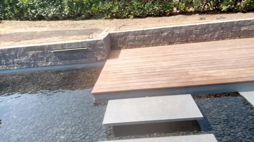 Hybridpool mit Natursteinelementen und Holzterrasse