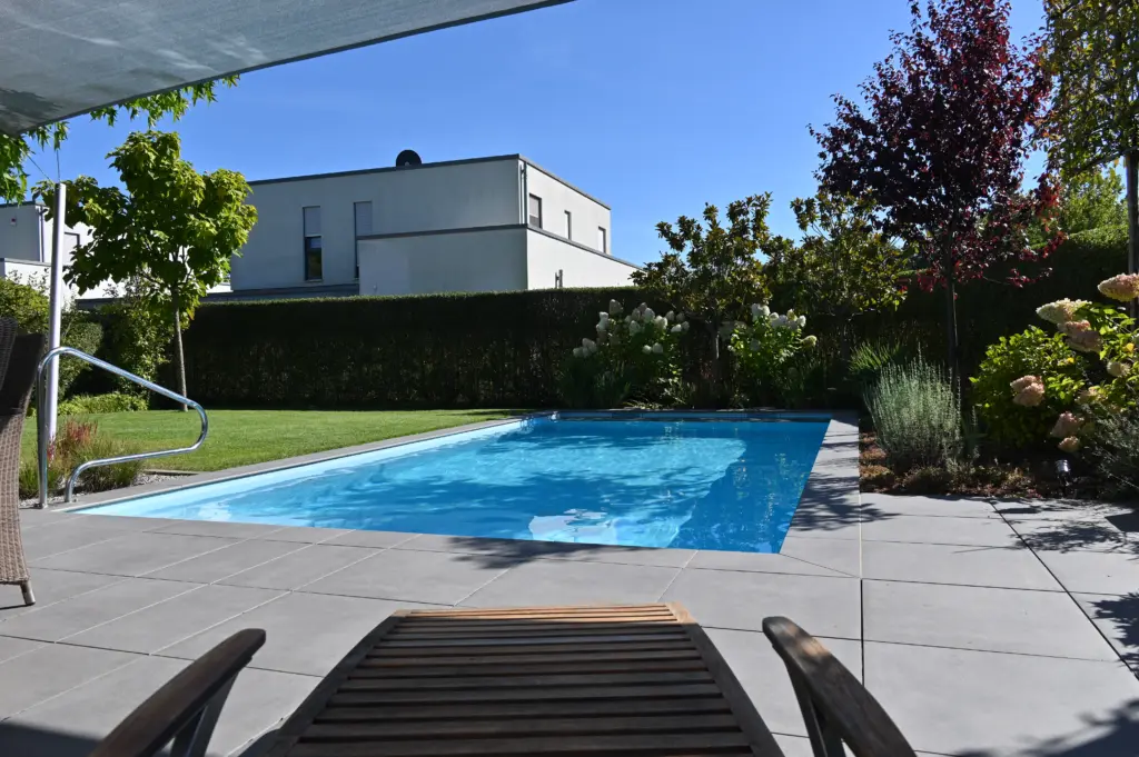 Poolanlage mit Blütengarten und Terrassenfläche