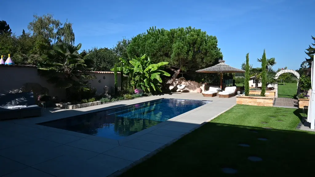Moderner Pool mit heller Terrassenfläche und Poolhaus