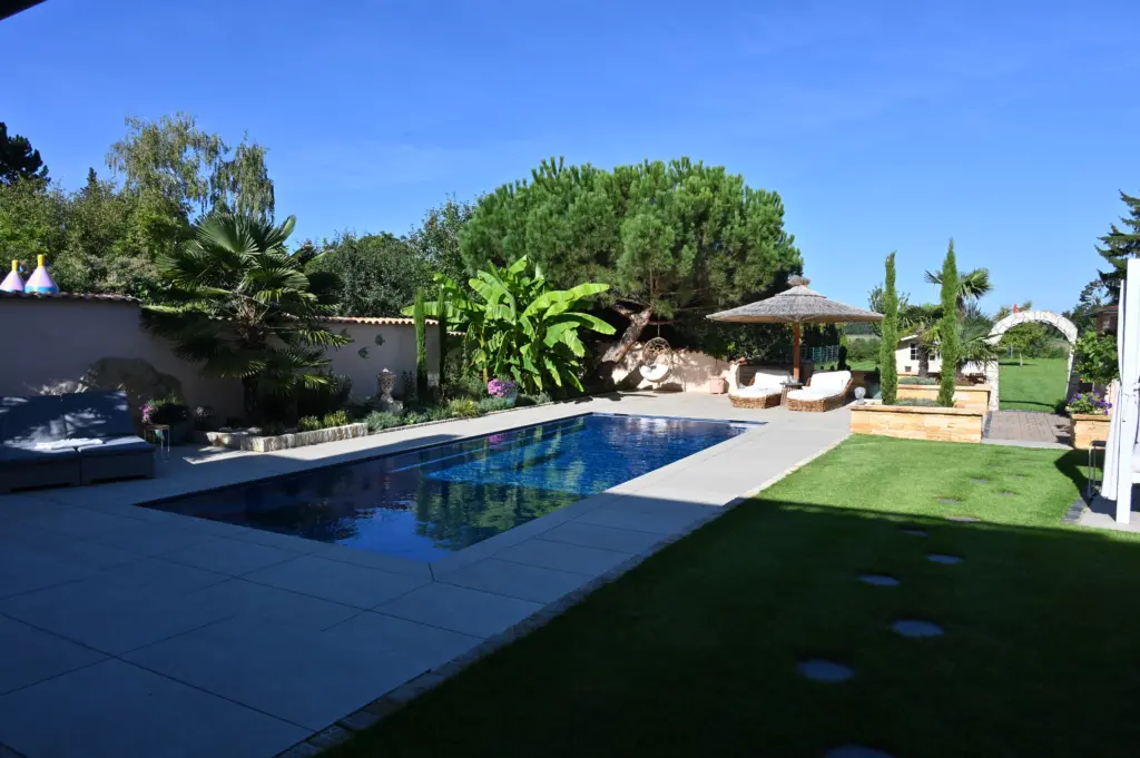 Moderner Pool mit heller Terrassenfläche und Poolhaus