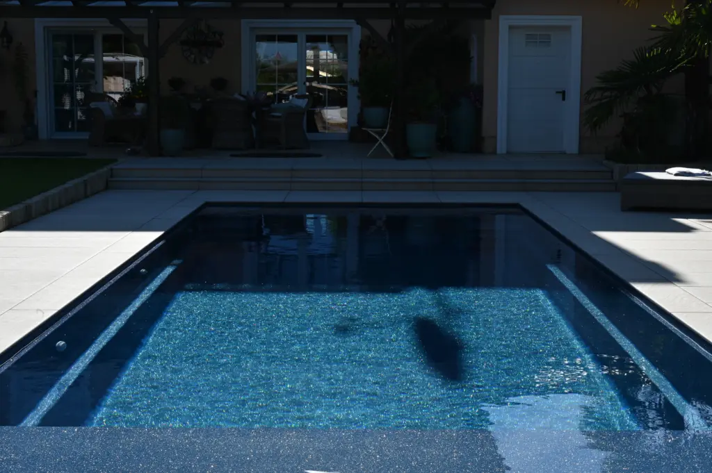 Moderner Pool mit heller Terrassenfläche und Poolhaus