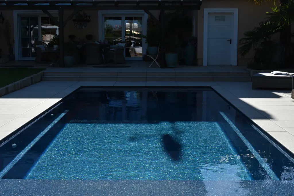 Moderner Pool mit heller Terrassenfläche und Poolhaus
