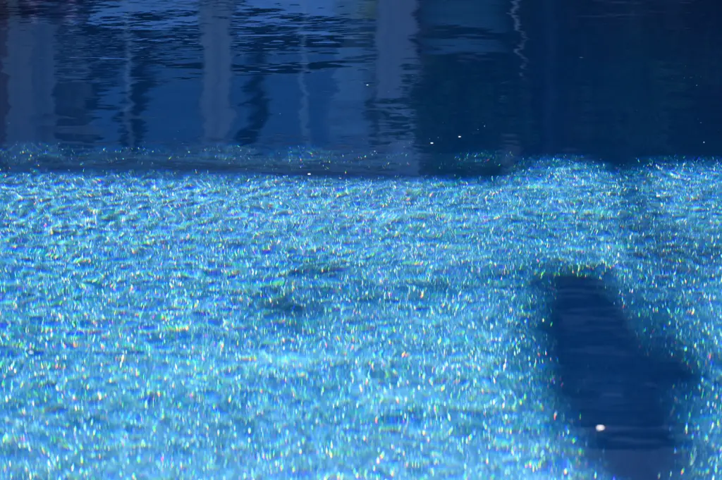 Moderner Pool mit heller Terrassenfläche und Poolhaus