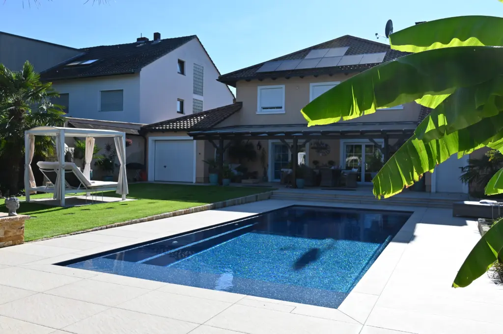 Moderner Pool mit heller Terrassenfläche und Poolhaus