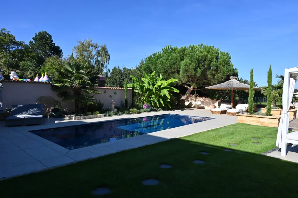 Moderner Pool mit heller Terrassenfläche und Poolhaus