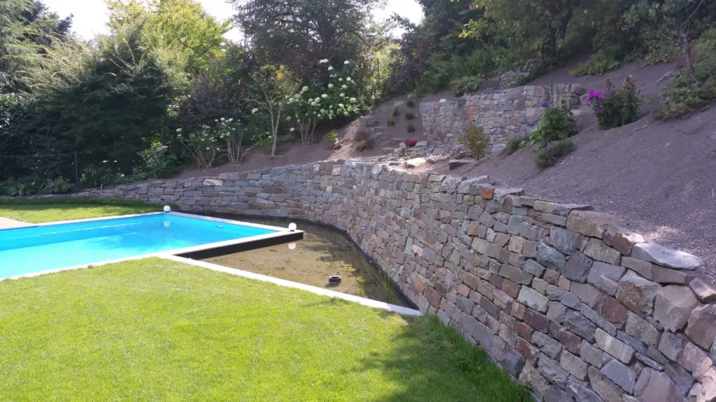 Pool mit Natursteinmauer und Holzbelag