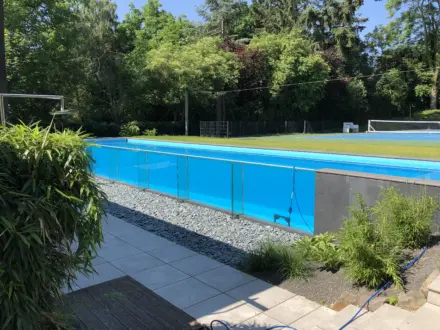 Langgestreckter Glaswandpool mit offener Wasserfläche