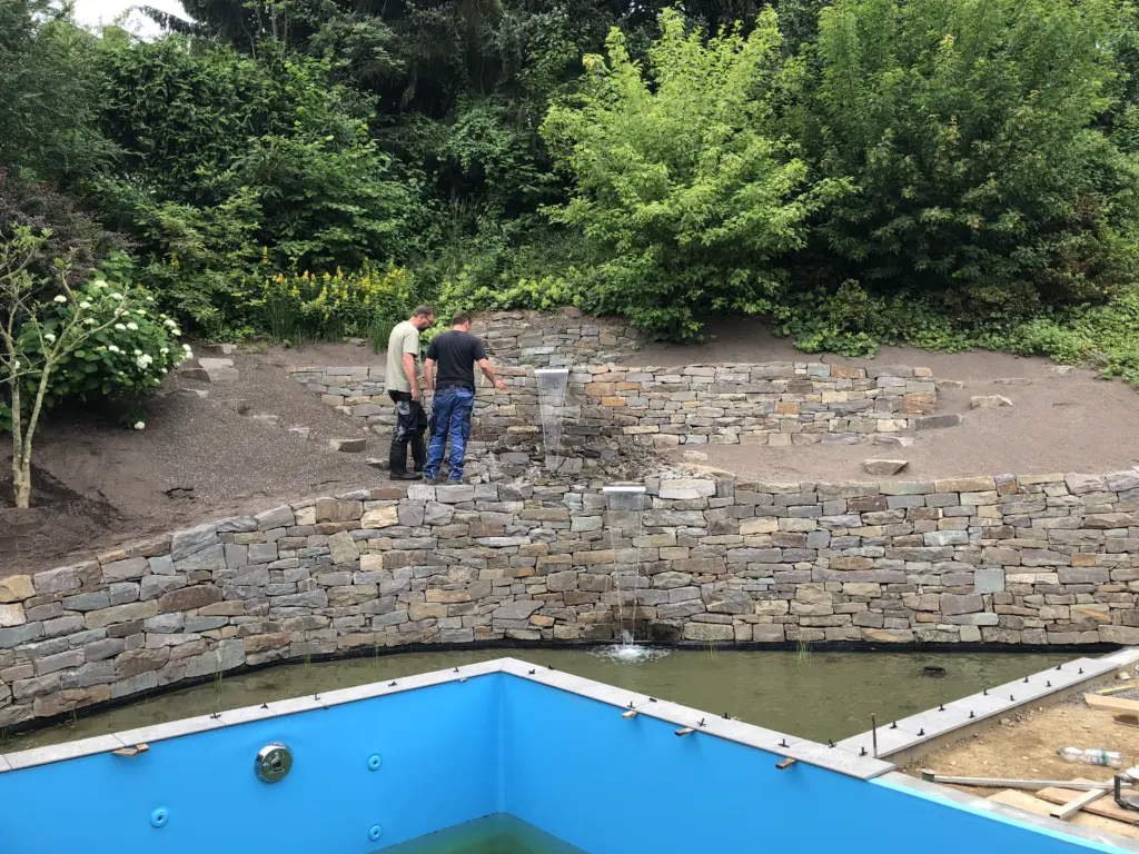 Pool mit Natursteinmauer und Holzbelag