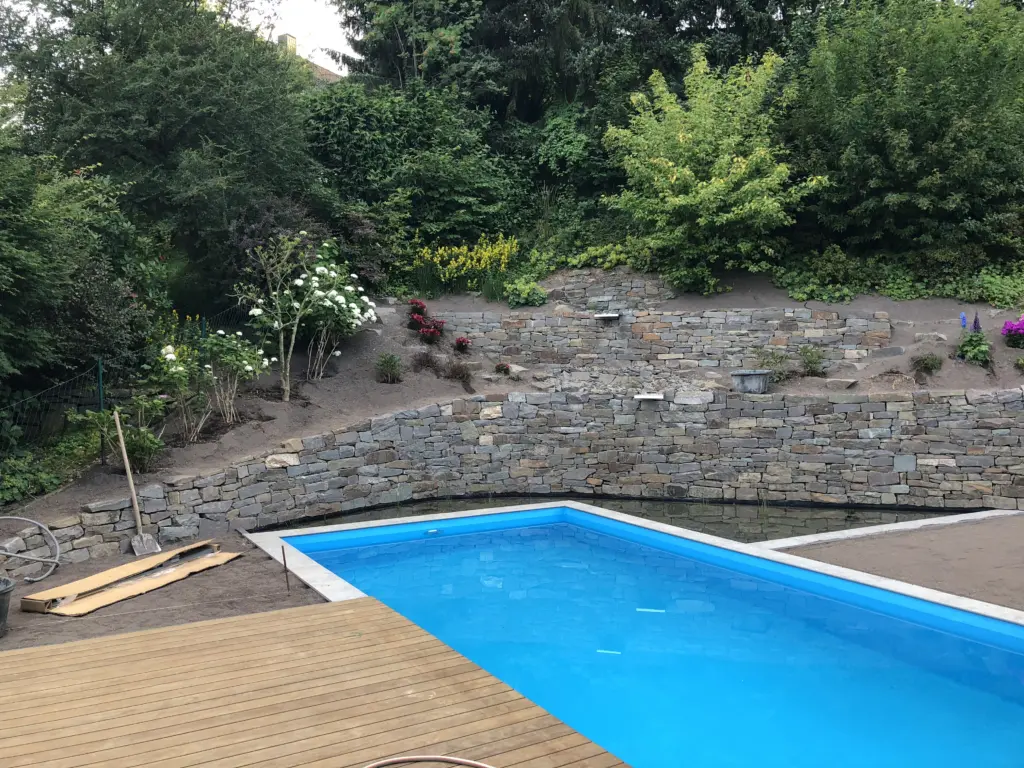 Pool mit Natursteinmauer und Holzbelag