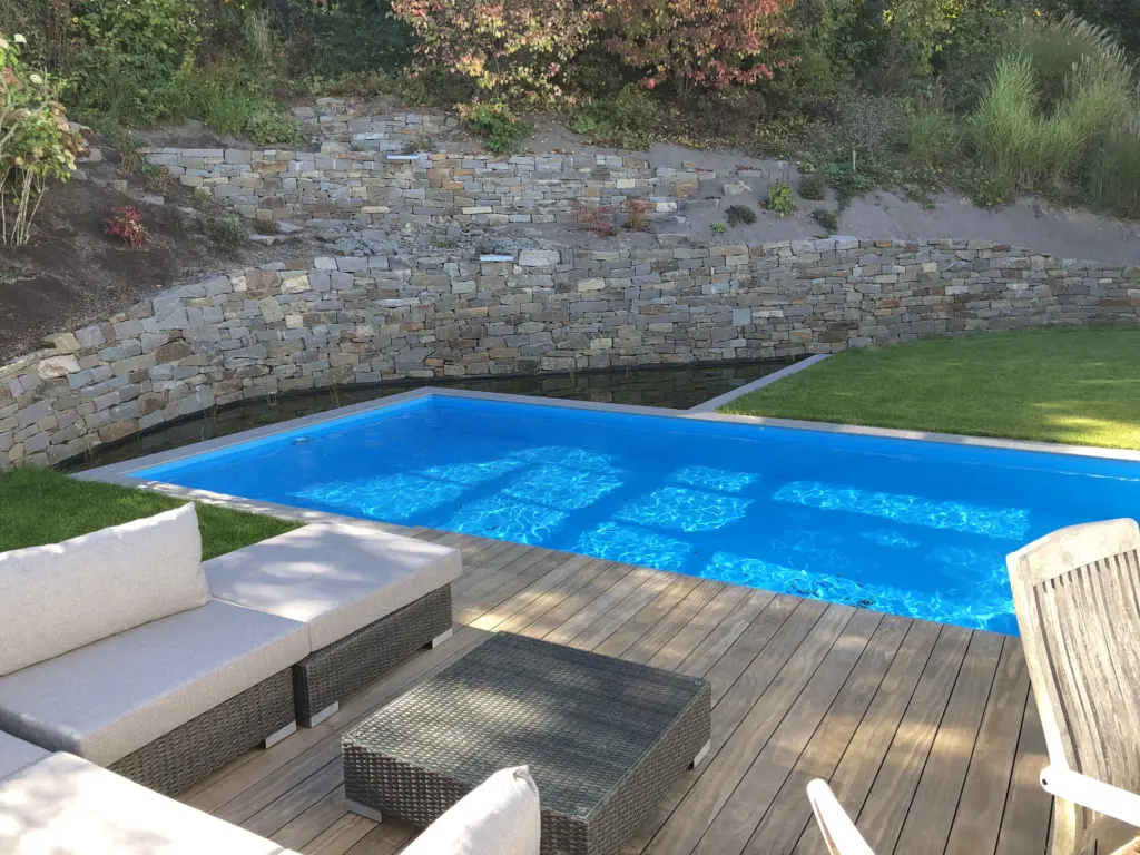 Pool mit Natursteinmauer und Holzbelag