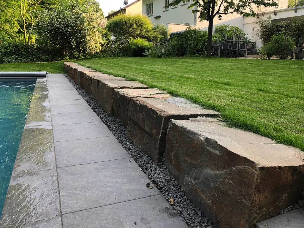 Pool mit Natursteinmauer und Terrassenbereich