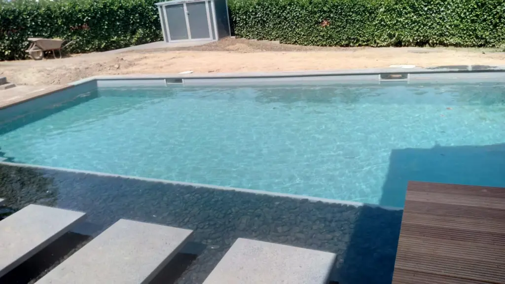 Hybridpool mit Natursteinelementen und Holzterrasse