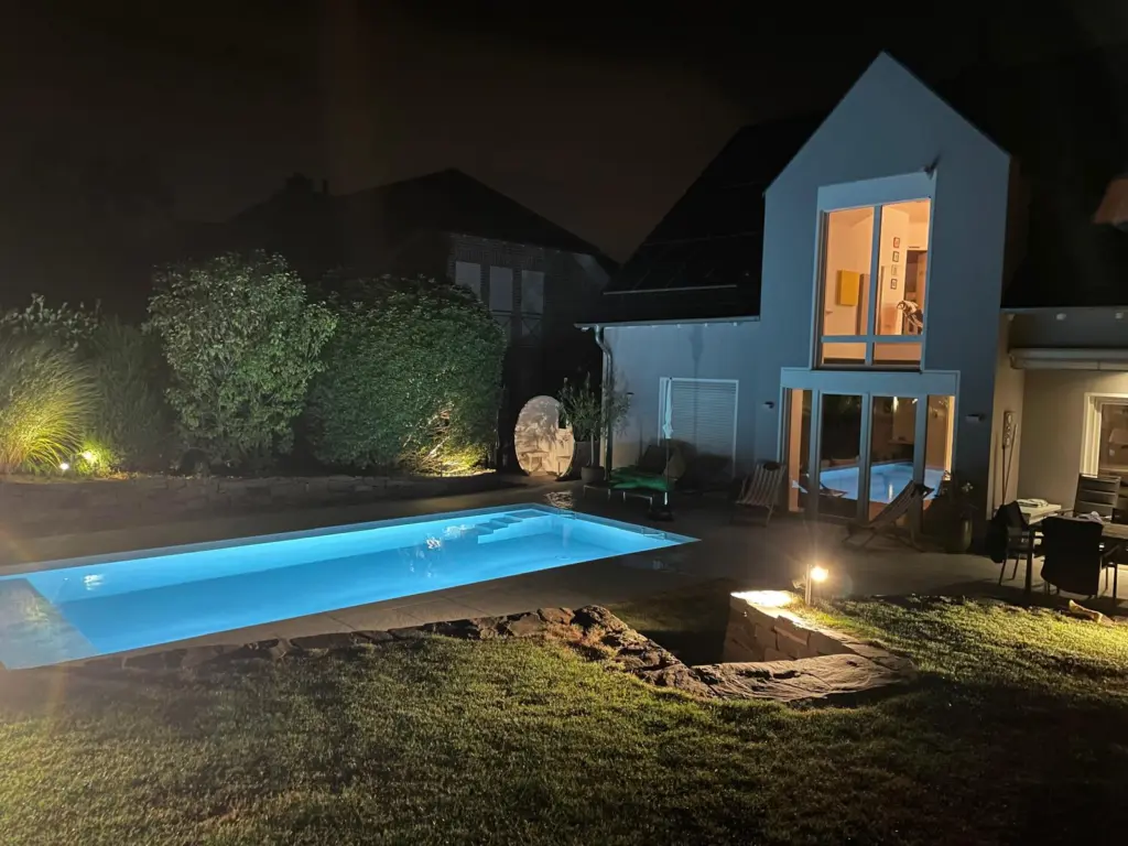 Salzwasserpool mit Abendbeleuchtung im terrassierten Garten