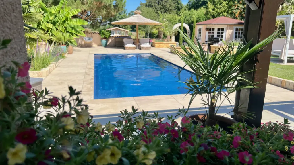 Moderner Pool mit heller Terrassenfläche und Poolhaus