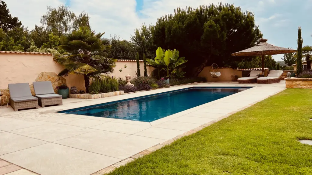 Moderner Pool mit heller Terrassenfläche und Poolhaus